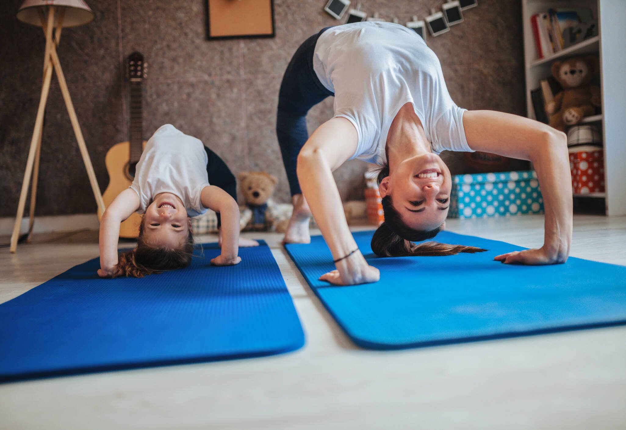 Moeder en dochter doen samen een yogapose in de woonkamer