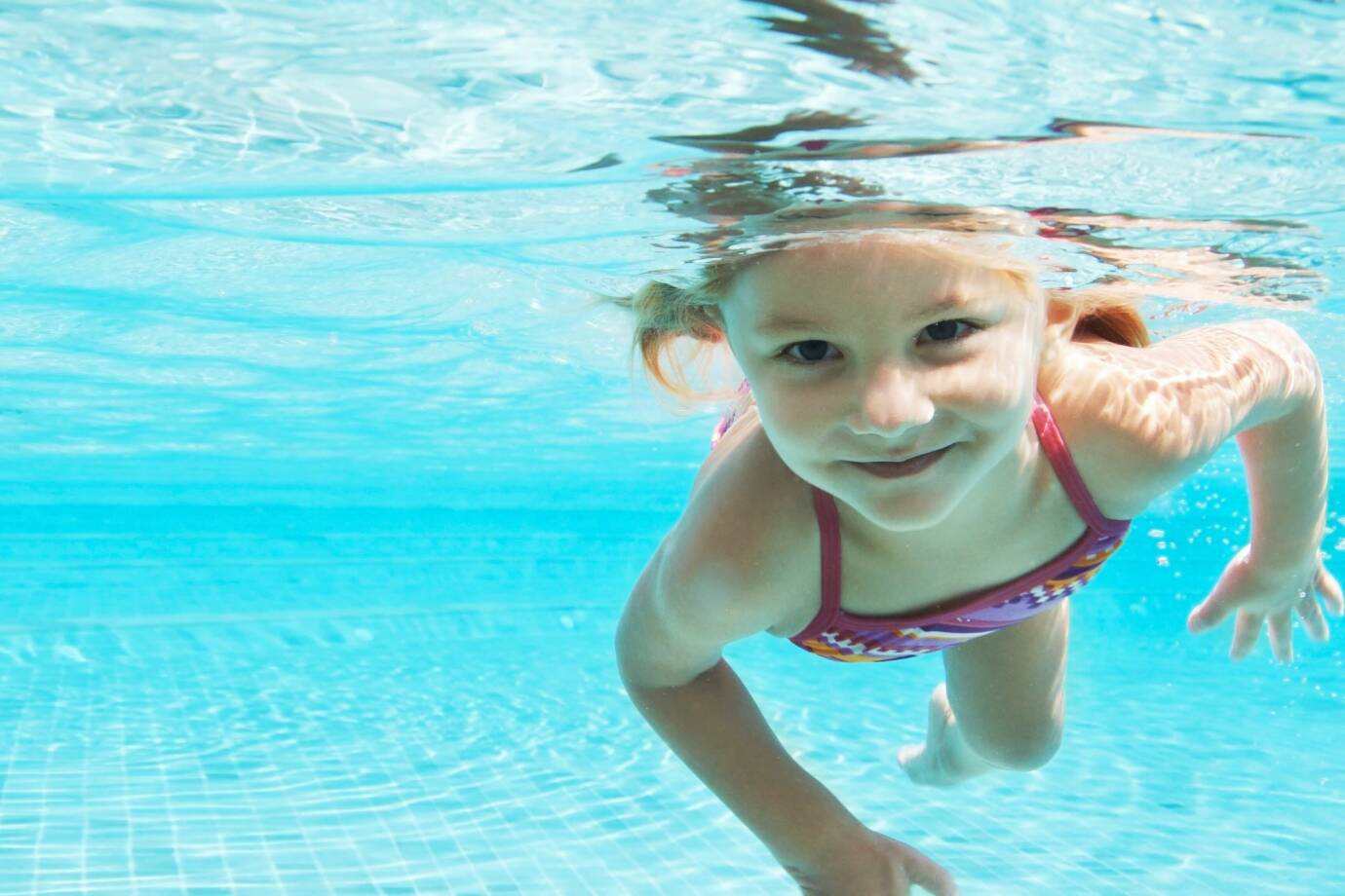 Een meisje zwemt glimlachend onder water