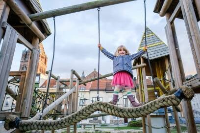 Een meisje speelt op een touwbrug in de speeltuin