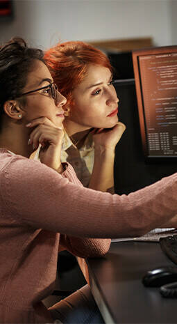 two women looking at computer screen thinking