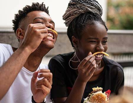 Two teenagers laughing while eating french fries