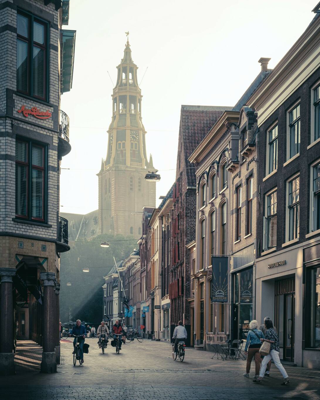 Foto van een straat in de binnenstad van Groningen met op de achtergrond de kerktoren.