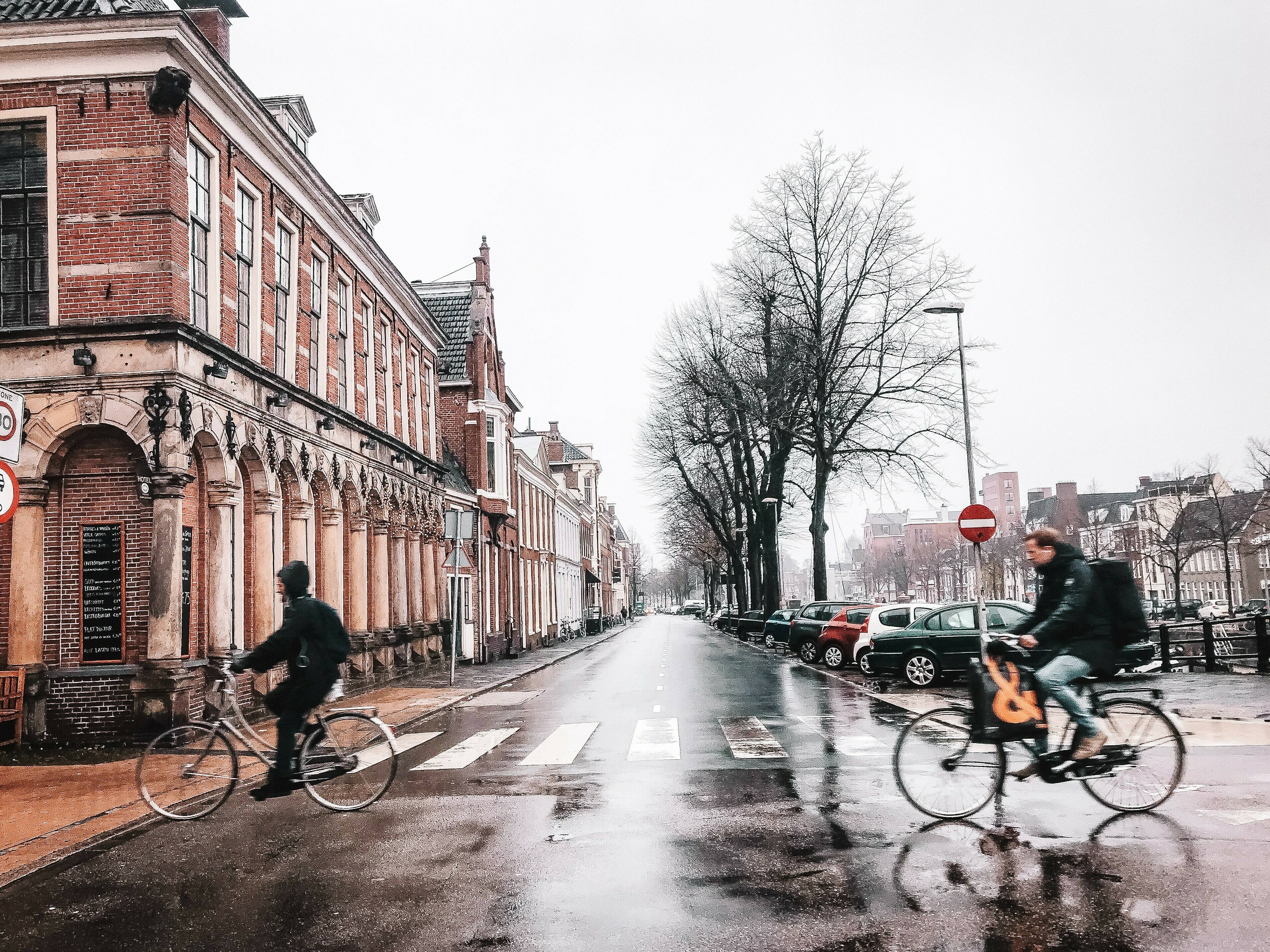 Twee fietsers die in de binnenstad op een regenachtige dag over de straat fietsen
