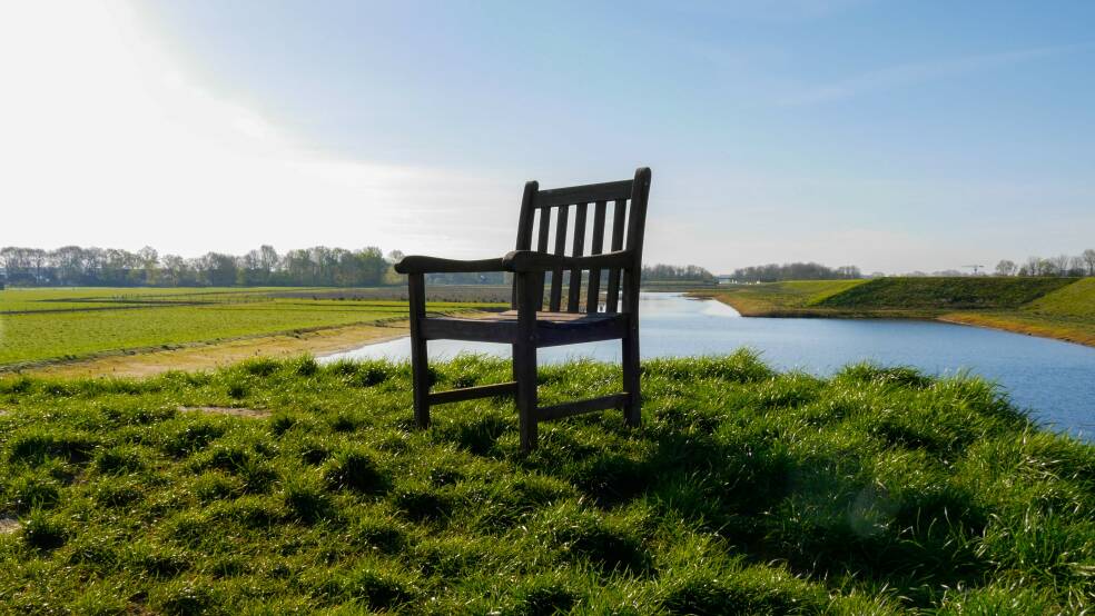 Beeld van een stoel wat helemaal leeg in een landelijk natuurgebied in het gras staat
