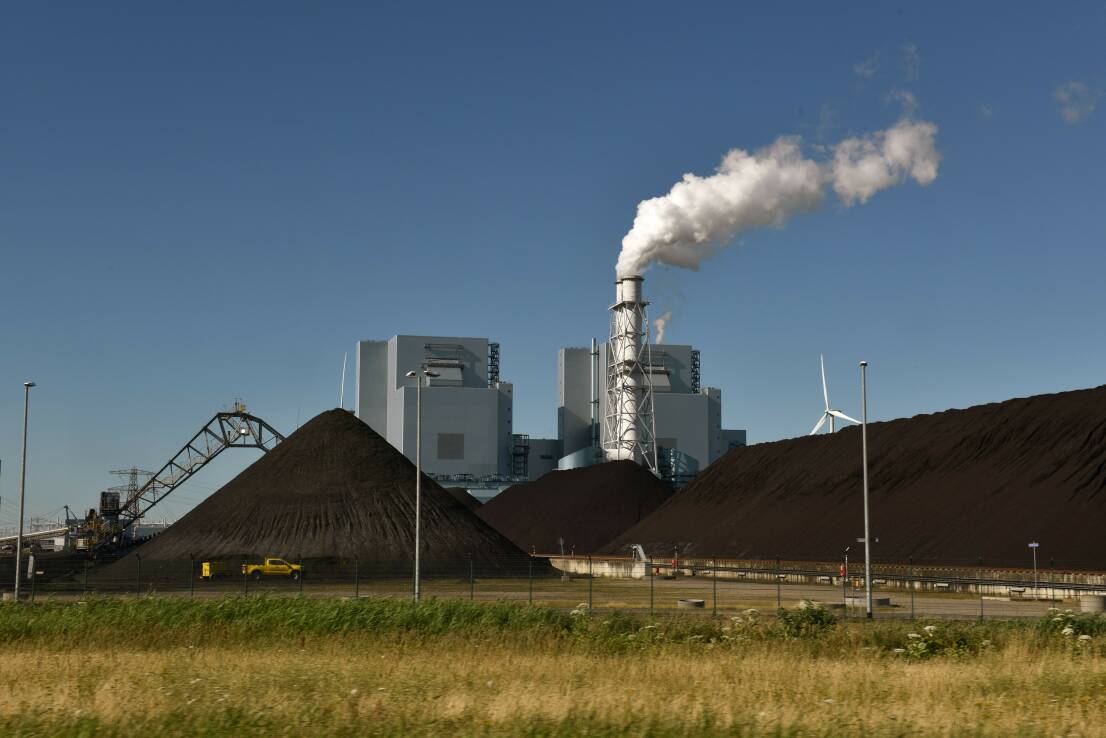 Beeld van een industrieel gebouw met een wit rokende schoorsteen