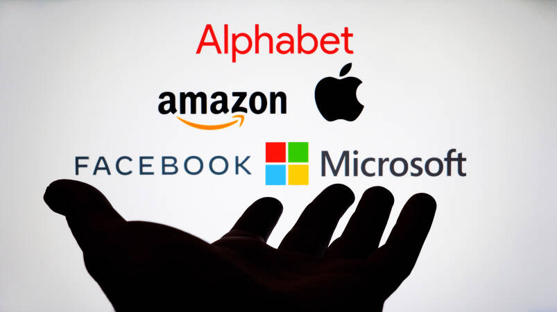 Silhouette van een hand met de logo's van alphabet, amazon, apple, facebook (meta) en microsoft