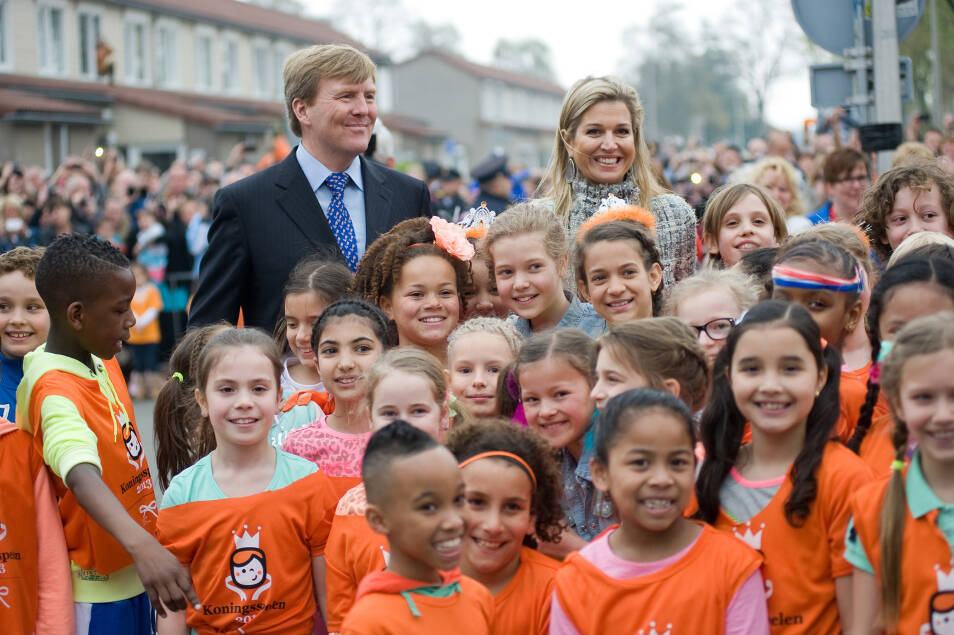 Willem Alexander en Maxima poseren met, in het oranje geklede, kinderen