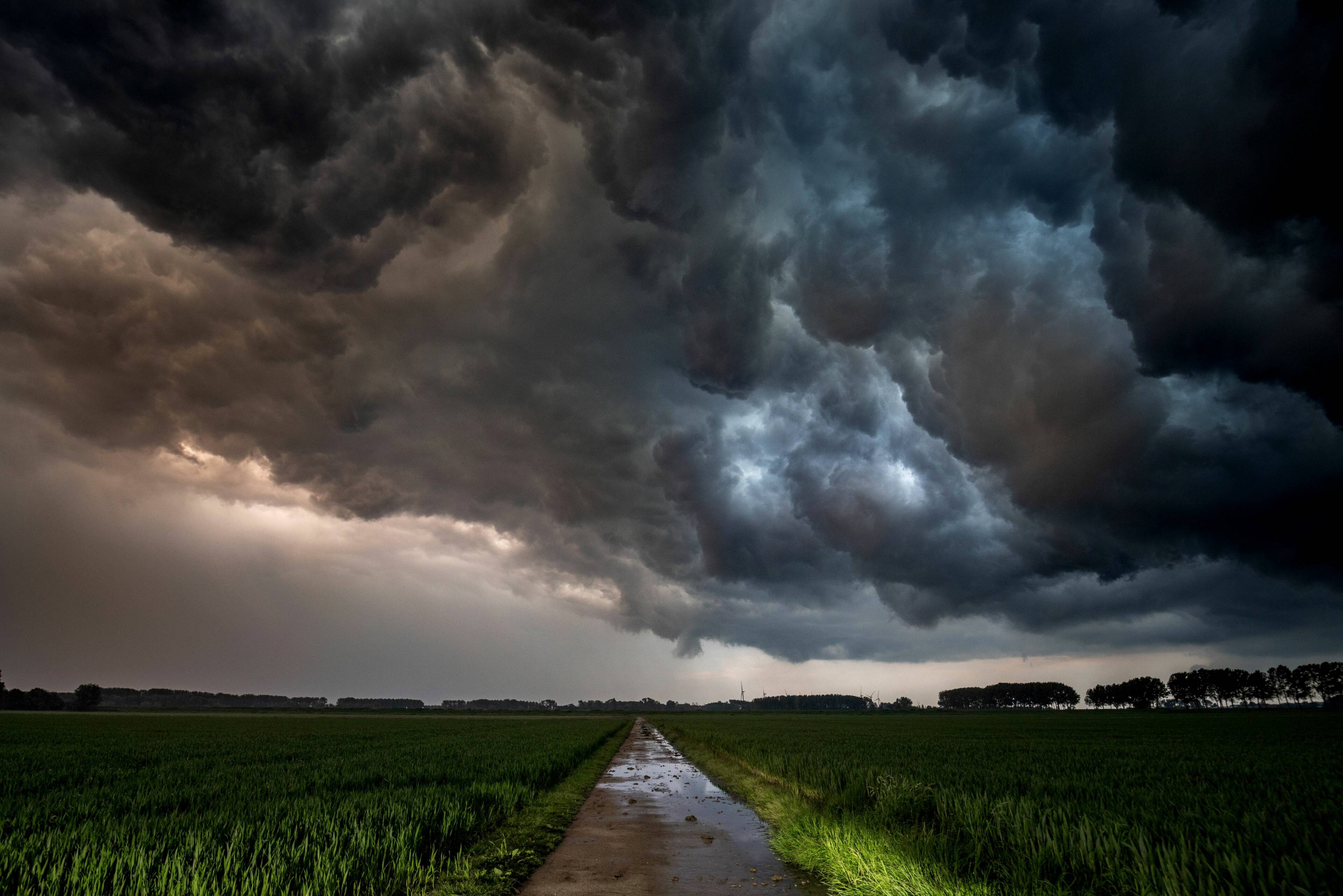 Foto van een onheilspellend donkere lucht met onweer boven een agrarisch landschap