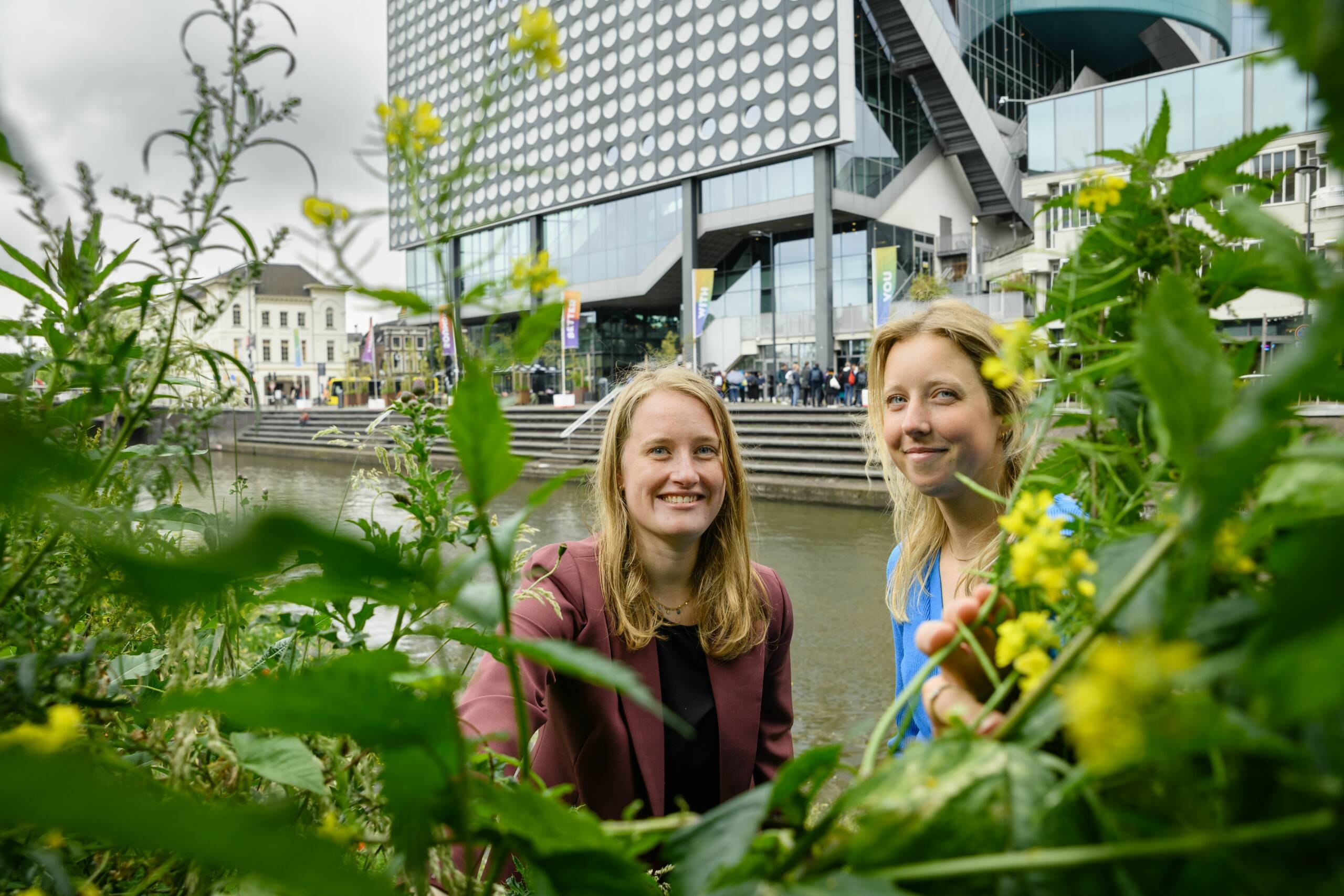 Foto van juriste Tessa Rötscheid en bestuurskundige Charlotte Offringa in het groen bij de gracht voor Muziekcentrum Vredenburg in Utrecht