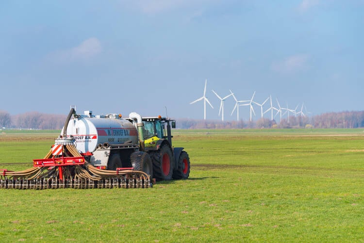 Foto van een traktor met aanhanger 
die mest impregeneert.