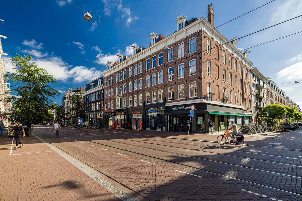 Hoekgebouw in de Ferdinand Bolstraat, gefotografeerd vanaf de overkant. Op de voorgrond is de bestrating goed te zien.