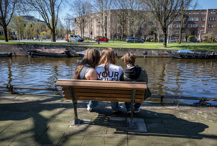 Drie jongeren op een bankje langs het water