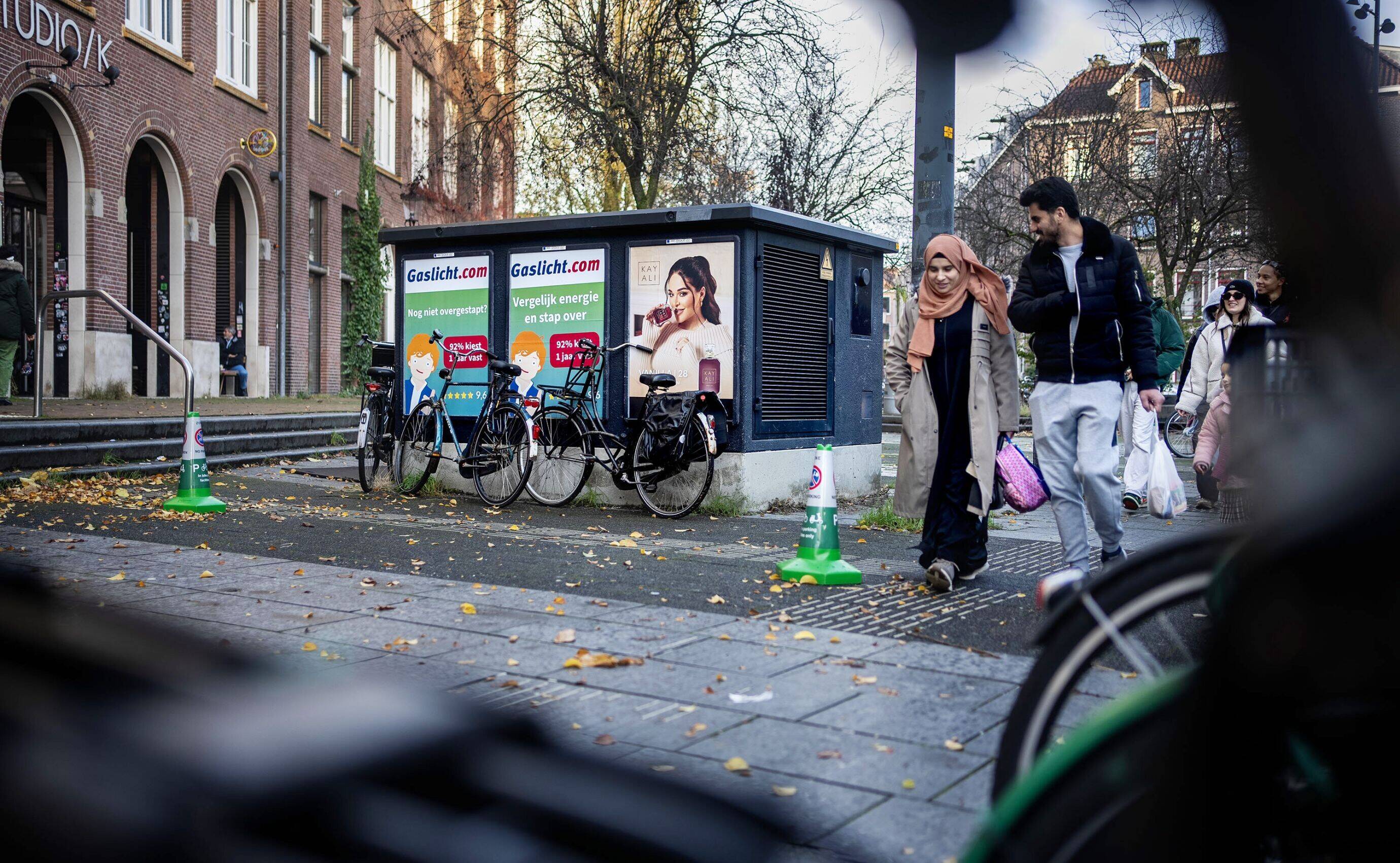 Elektriciteitshuisje in Amsterdam, mensen wandelen voorbij