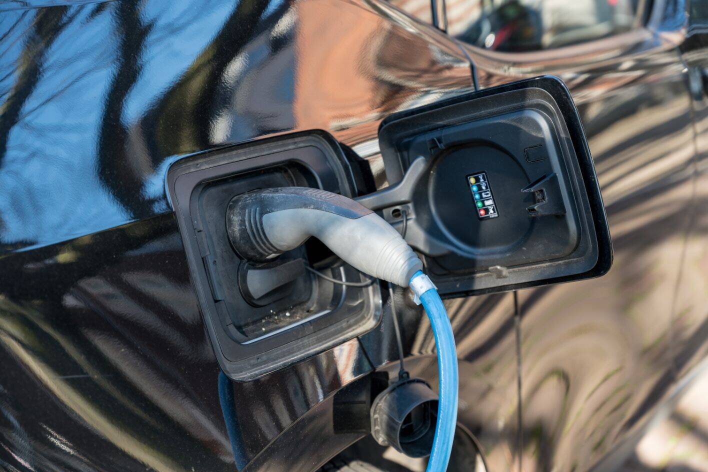 Closeup auto opladen. Op slimme tijden de auto opladen ontlast het elektriciteitsnet, bijvoorbeeld buiten piekuren.