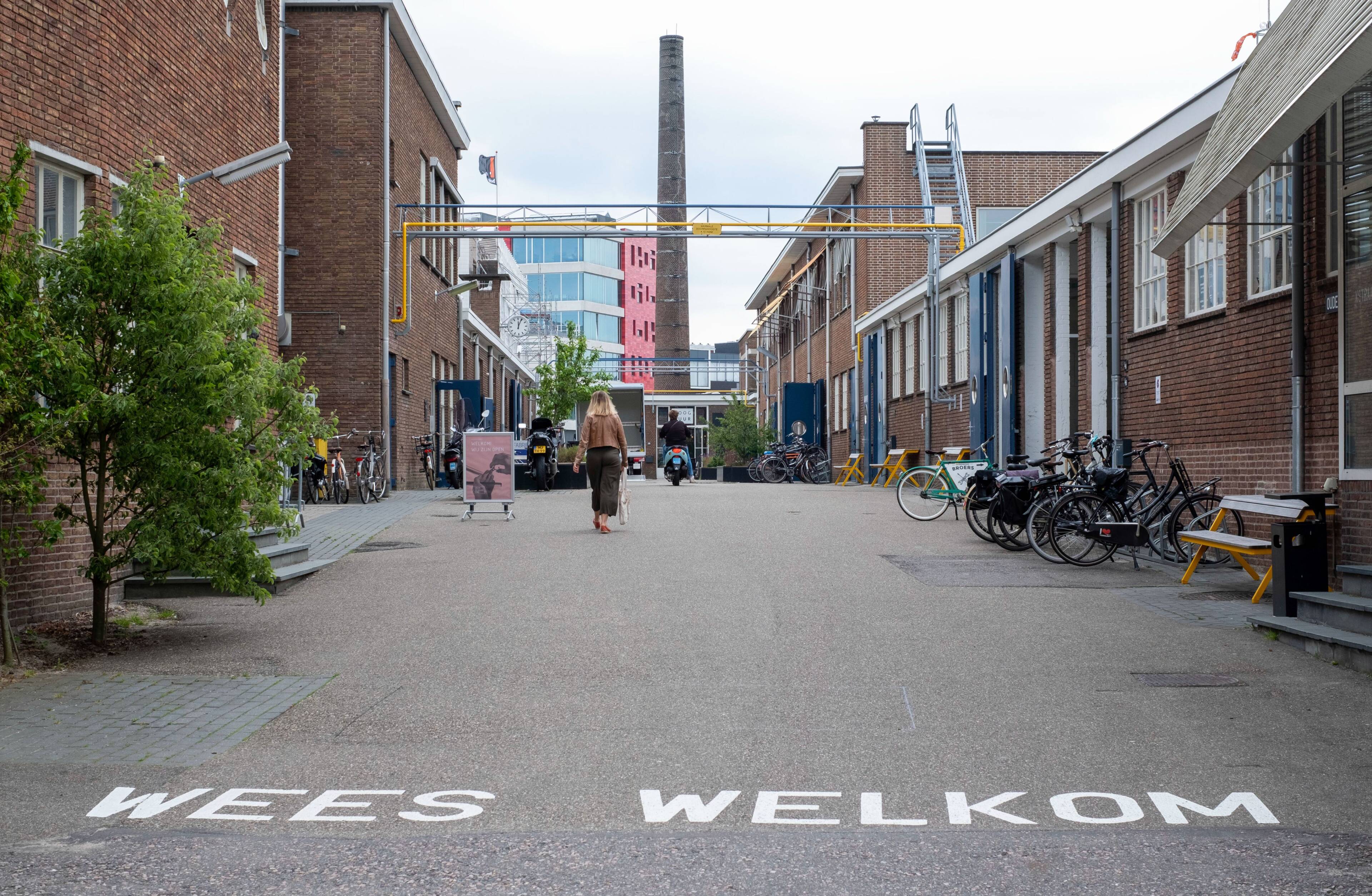 Woonwijk in de stad, op straat is 'Wees Welkom' te lezen in grote, witte letters.