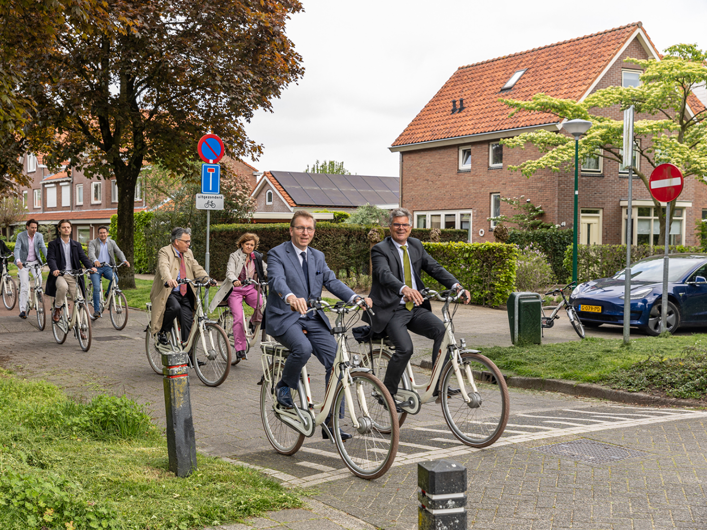 De commissaris met een groep mensen op de fiets bij het bezoek aan het Franse gat