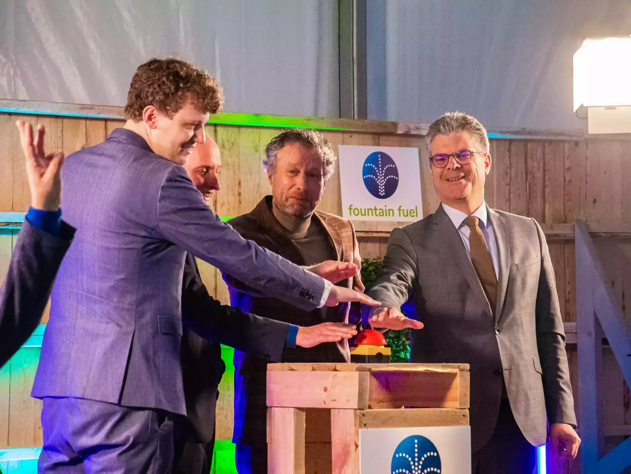 De commissaris en drie andere mensen drukken samen op een grote rode knop bij de start van de bouw van het waterstofstation in Amersfoort op 21 oktober.