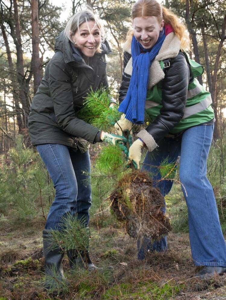 Mirjam Sterk plant een boom in een bos met een vrijwilligster