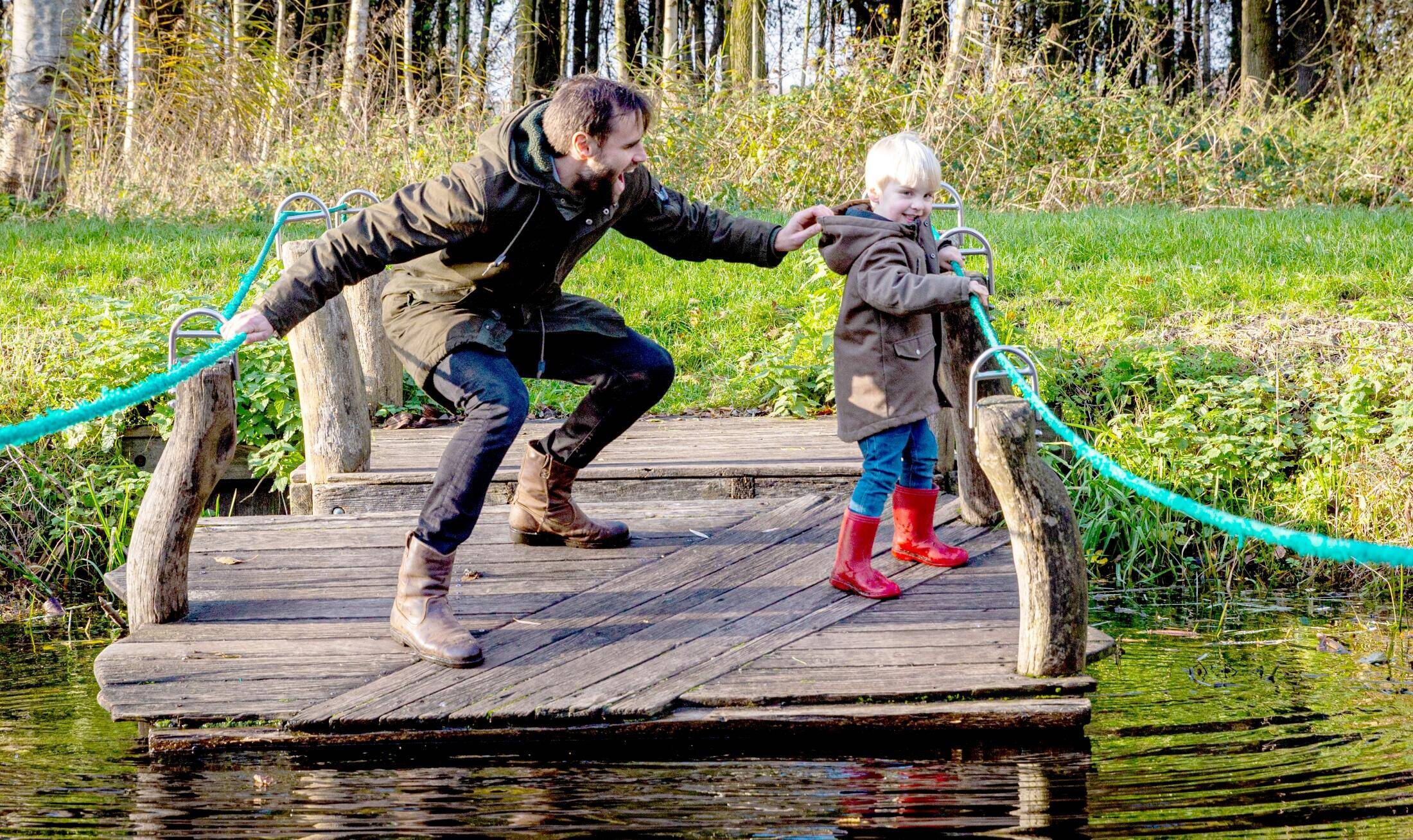 Een vader en zoon steken een water over met een trekvlot