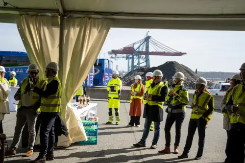 Personer med hj&auml;lm och reflexv&auml;st vid invigning av Skandiaporten i Skandiahamnen.
