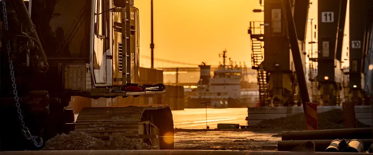 An excavator at the worksite with a sunset in the background.