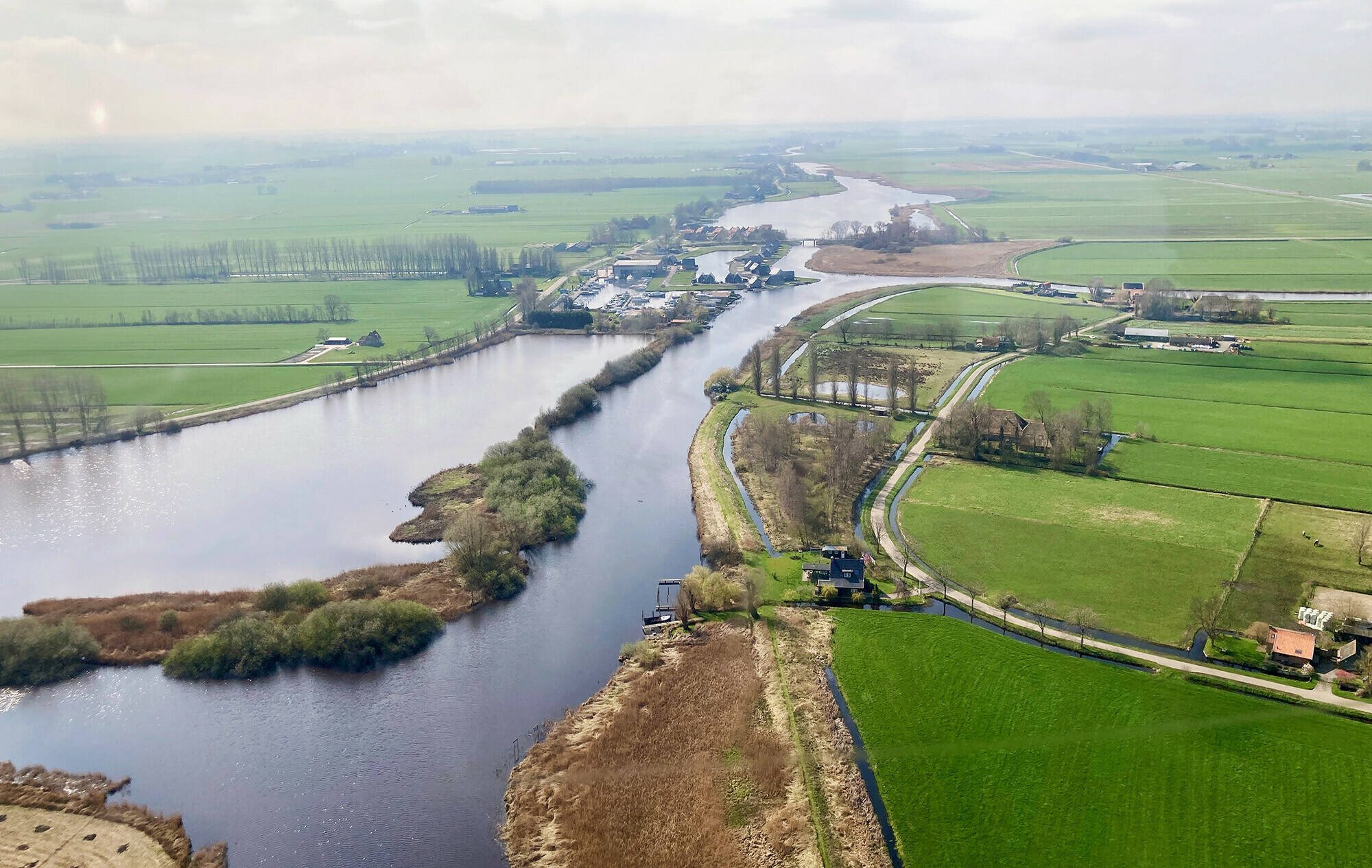 Luchtfoto van de Urkervaart, met rechts akkers en links bebouwing