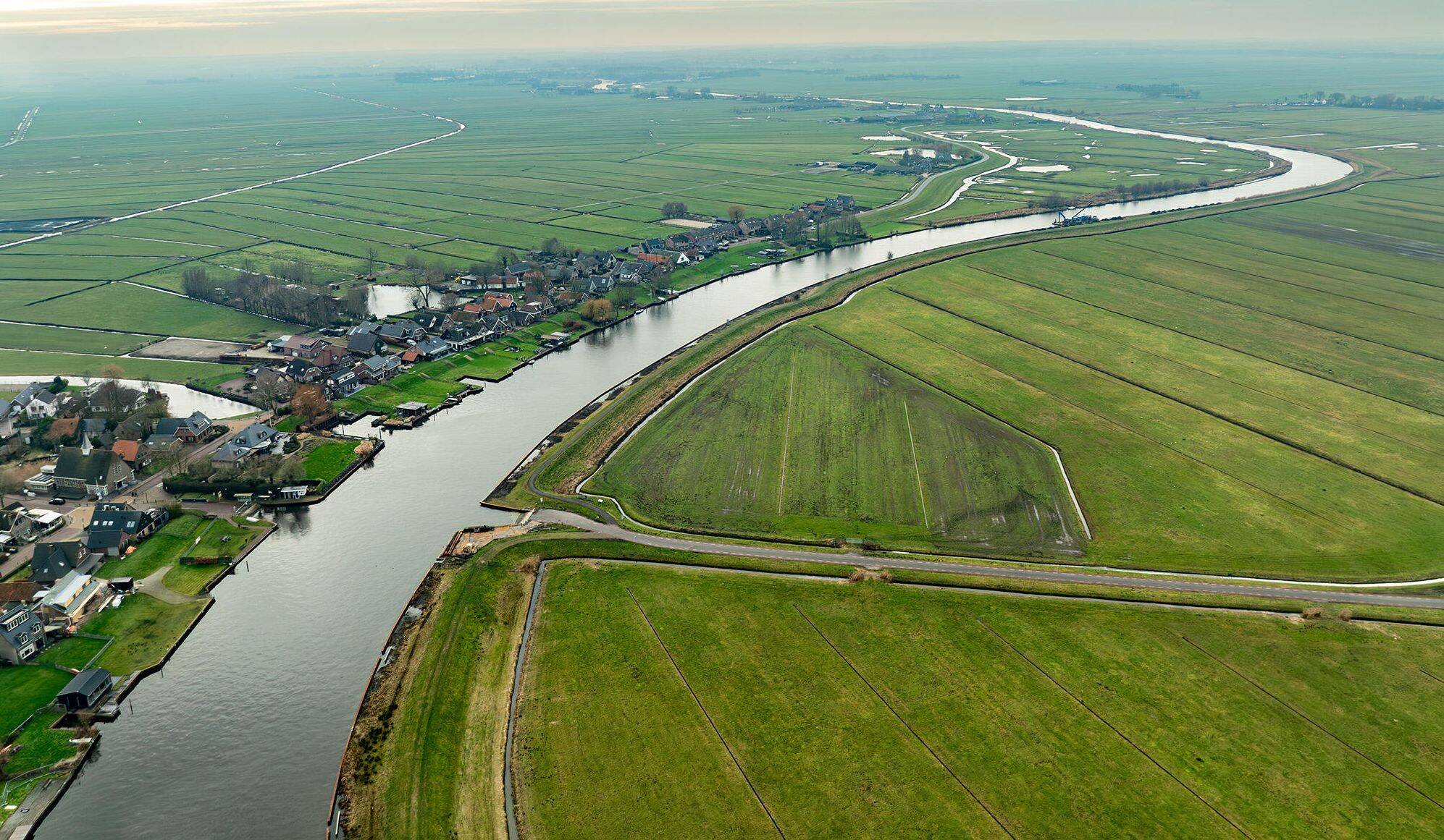 Luchtfoto van de Urkervaart, met rechts akkers en links bebouwing