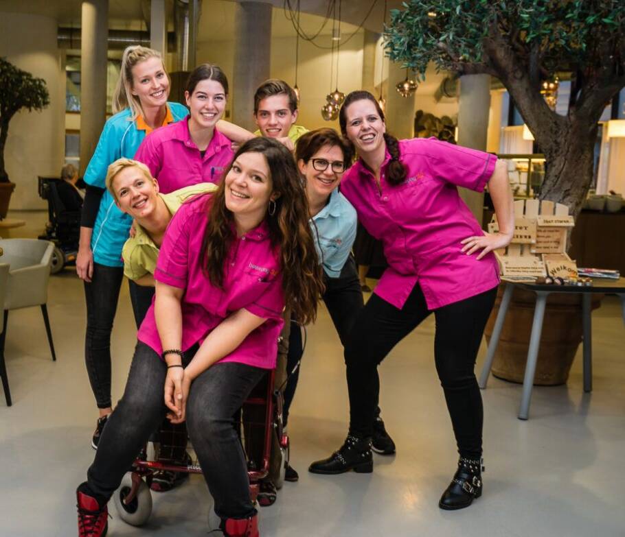 Foto van een groep medewerkers van Beweging 3.0, die lachend in de camera kijken.