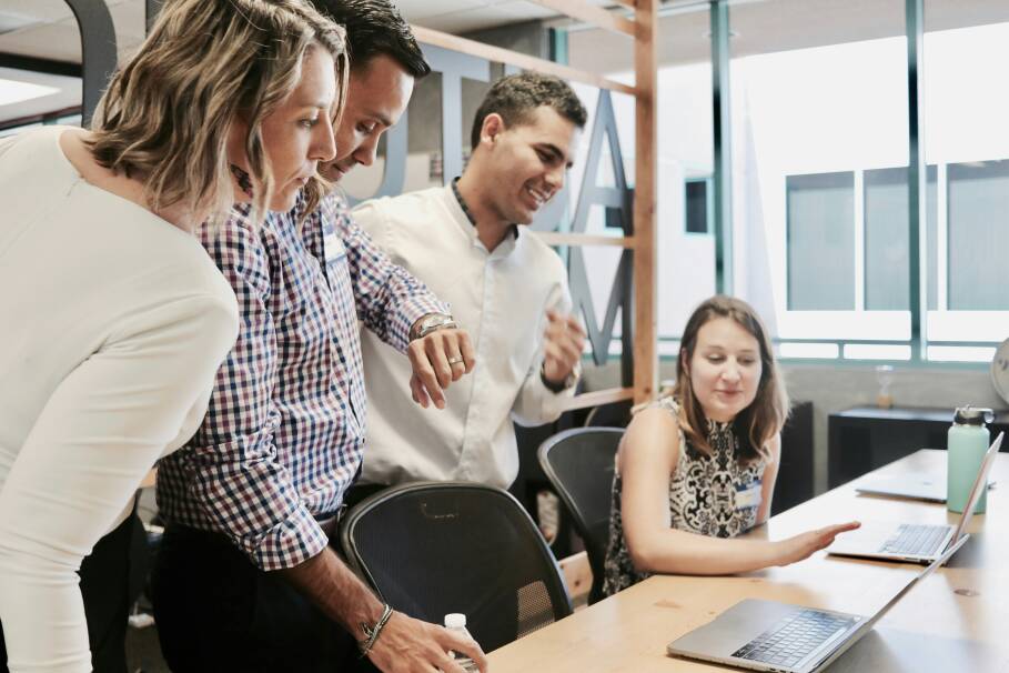 Foto van collega’s die samen kijken naar een laptopscherm en overleggen.