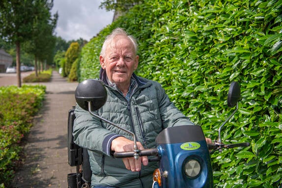 Foto van een oudere mevrouw die in een kamer op een hometrainer zit