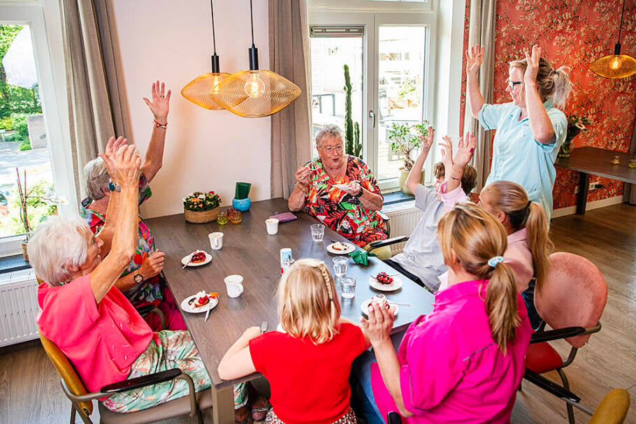 Foto van een oudere mevrouw die lachend met haar armen omhoog beweegt.