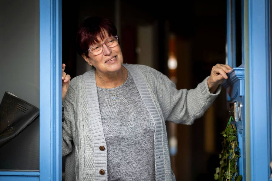 Foto vrouw die vrolijk de deur open doet