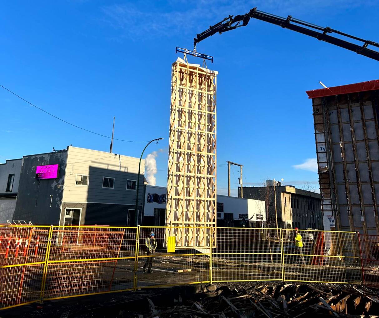 A crane carries a pre-fab panel