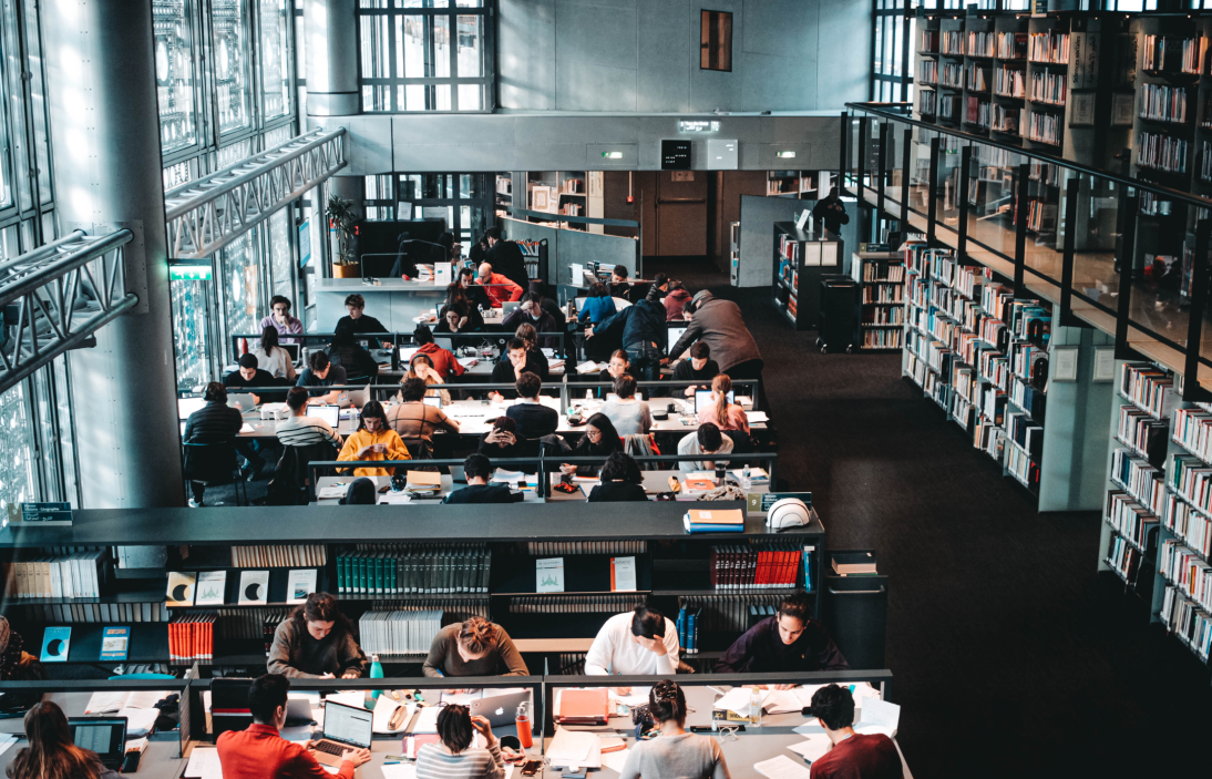 afbeelding van jongeren die aan lange tafels zitten in een bibliotheek