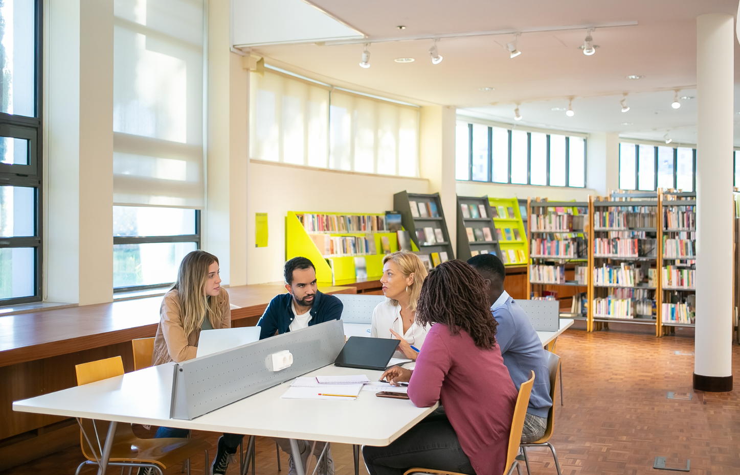 studenten met elkaar in gesprek aan tafel in een bibliotheek