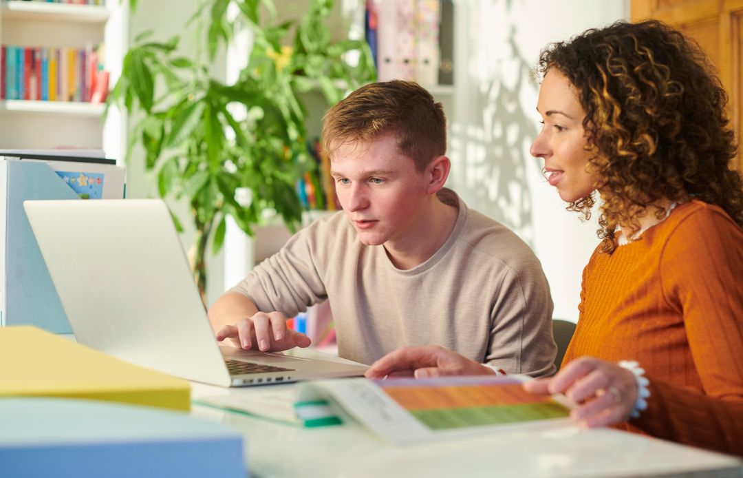 Student achter laptop met ernaast een begeleider die meekijkt