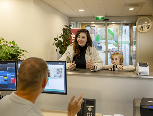 Een moeder met kind staat aan de servicebalie bij het Stedelink hoofdkantoor