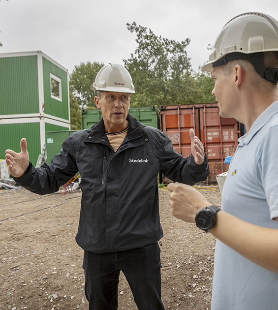 We zien twee stedelink medewerkers op de bouwplaats in gesprek