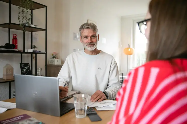 Medewerker bespreekt financi&euml;n met huurder tijdens gesprek met budgetcoach.