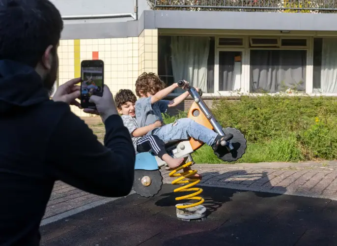 Twee kinderen spelen op wip in de wijk.