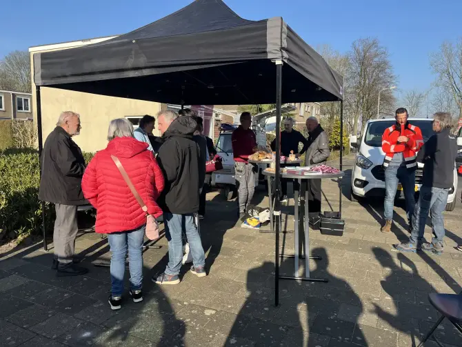 Bewoners praten met medewerkers tijdens een reparatiemiddag in de wijk.