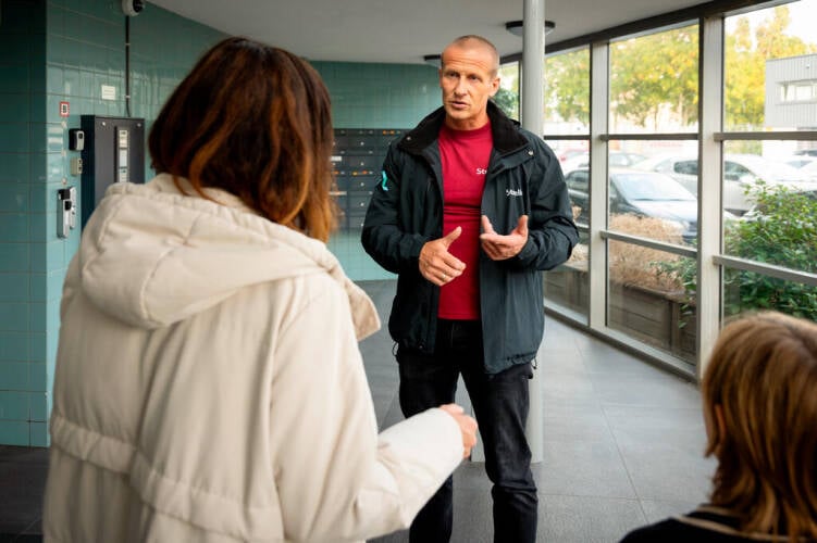 Medewerker spreekt met bewoners over brandveiligheid in woongebouw.