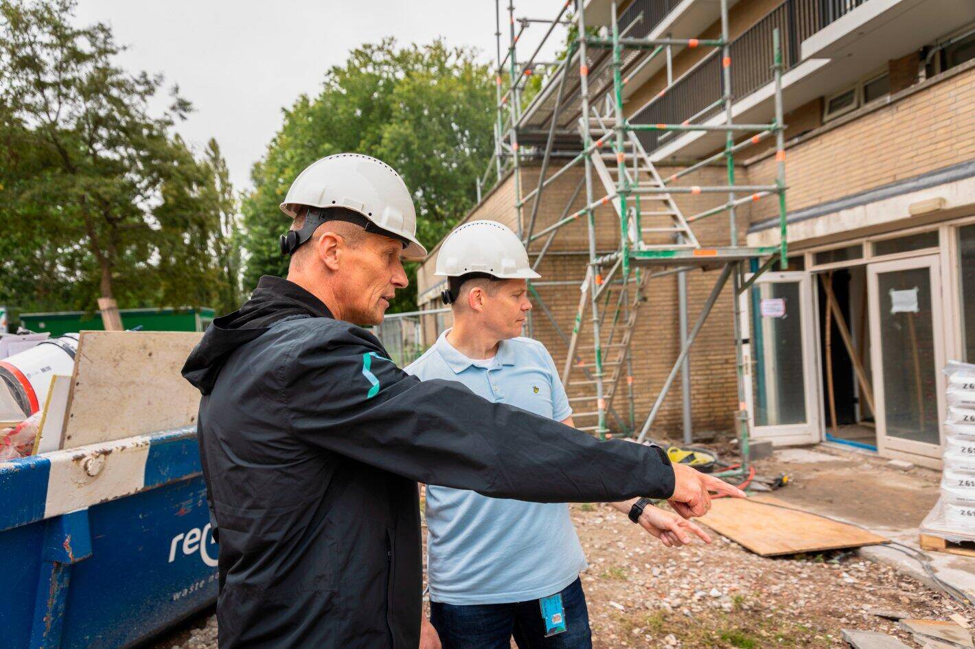 Een medewerker van Stedelink inspecteert samen met een aannemer een bouwplaats.