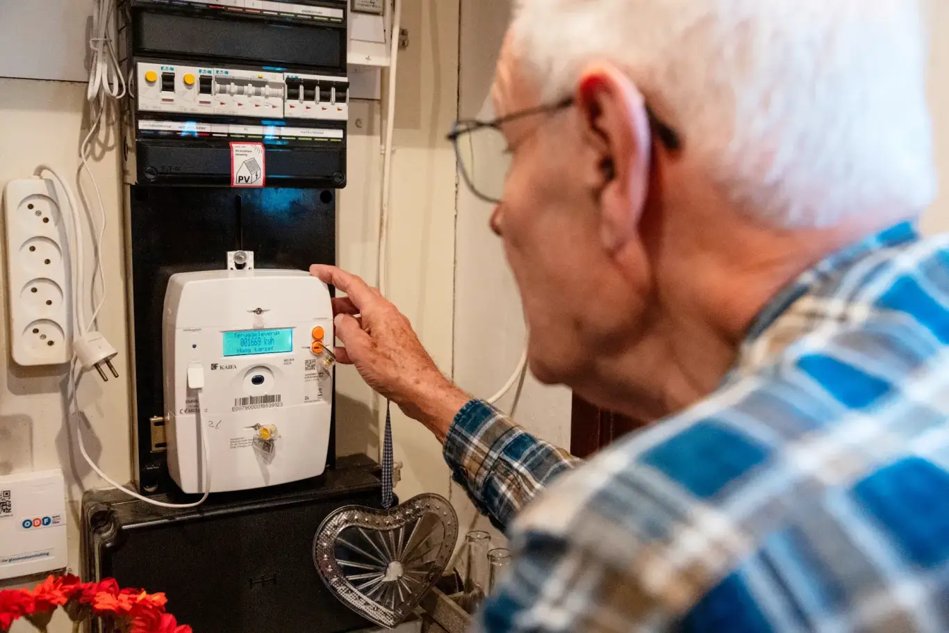 Persoon bekijkt en bedient slimme energiemeter in meterkast van woning.