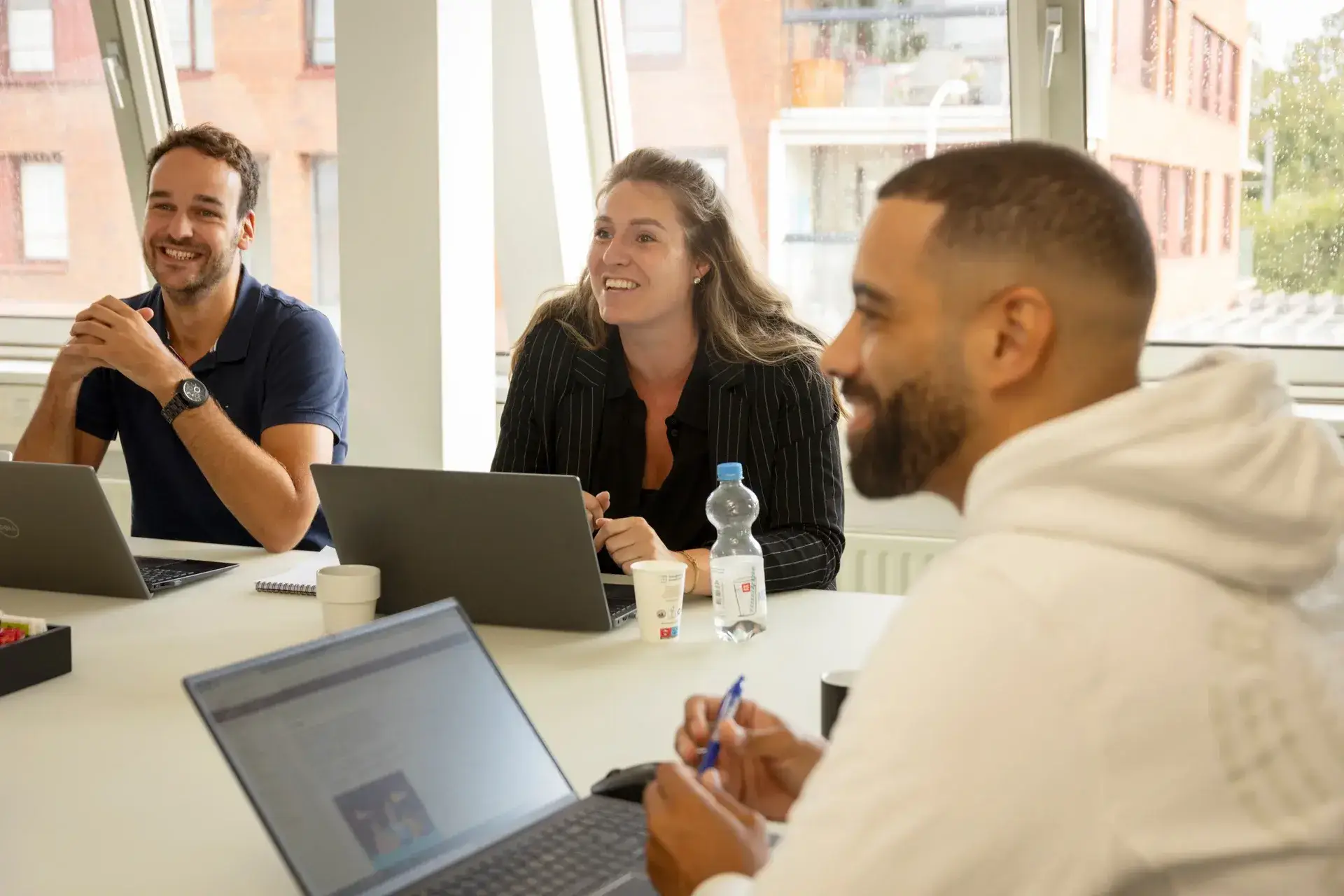 Collega&rsquo;s zitten samen aan tafel met laptops en overleggen tijdens teamoverleg op kantoor.
