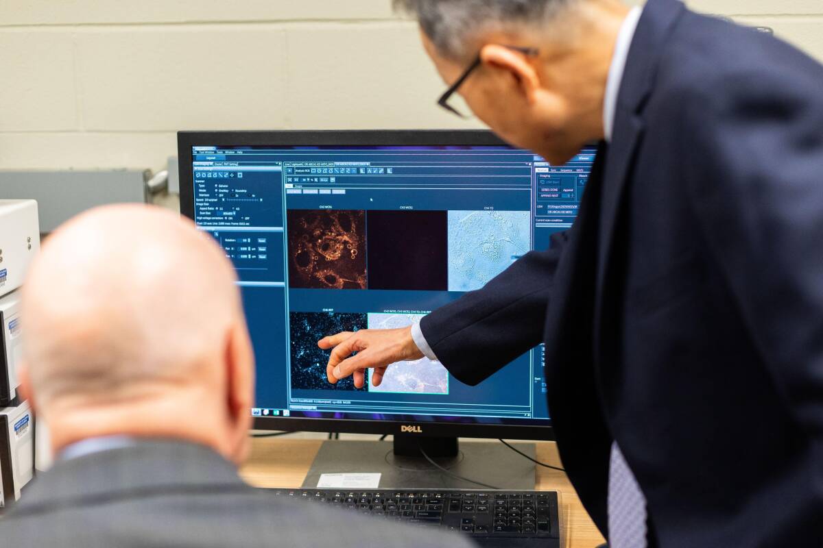 Dr. Wonhwa Cho and Dr. Herb Paaren are looking at a monitor.