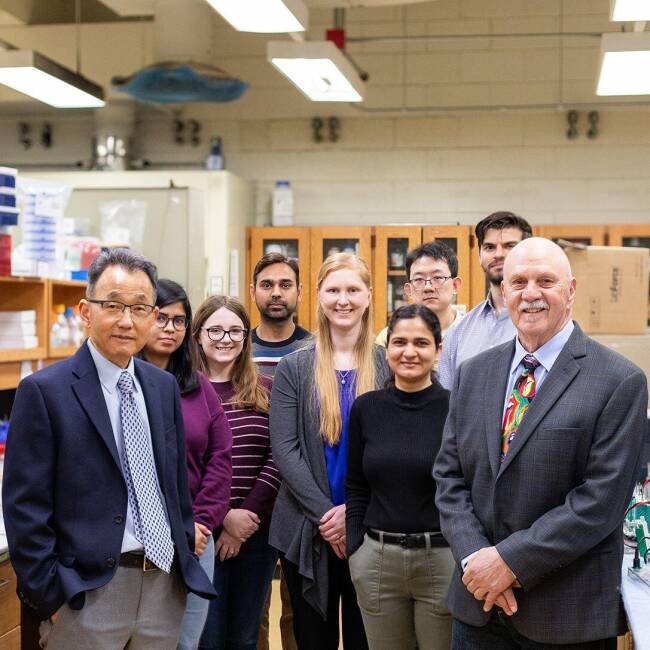 Dr. Wonhwa Cho at far left, and Dr. Herb Paaren at far right, pictured with lab staff.