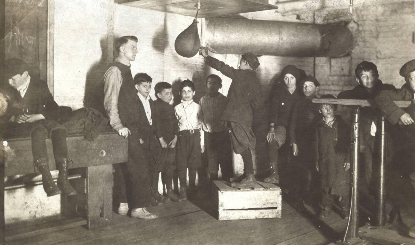Boy demonstrating a punching bag to young boxers, Marcy-Newberry Association records.