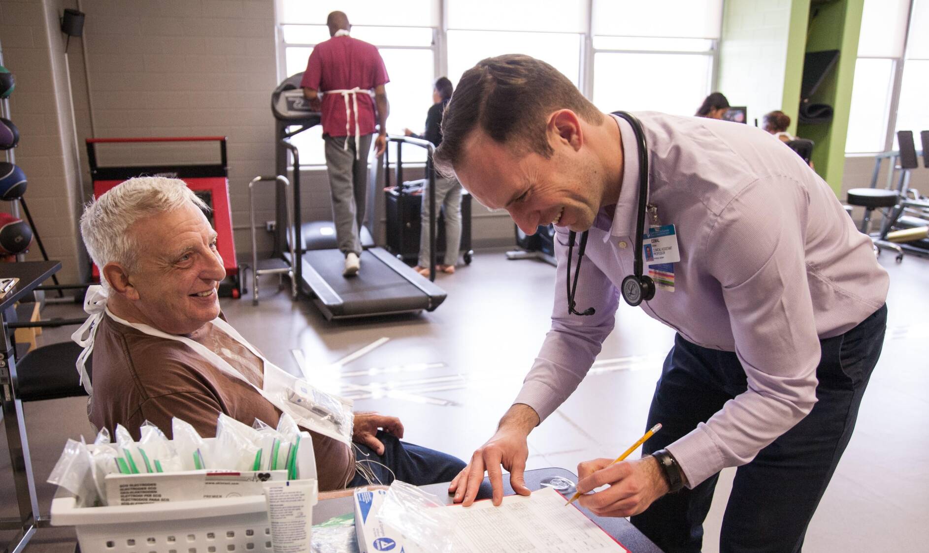 Medical professional signing papers next to a client sitting in a chair