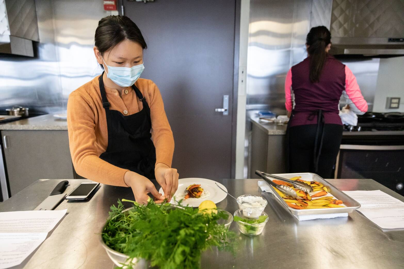 Person wearing a mask preparing food in an industrial kitchen